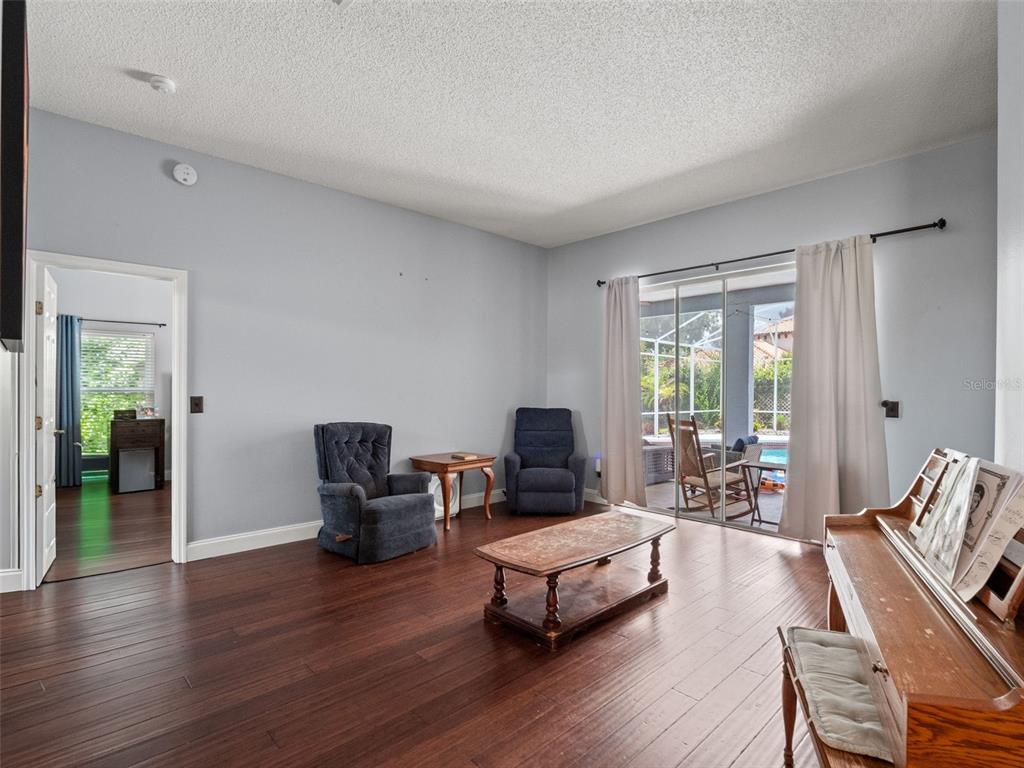 A living room features dark wood flooring, two blue armchairs, a coffee table, and sliding doors — 4353 STEED TERRACE, WINTER PARK, FL