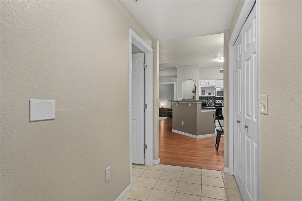A tiled entryway leads to a kitchen with wood-look flooring and a breakfast bar — 6663 QUEENS BOROUGH AVENUE UNIT 104, ORLANDO, FL