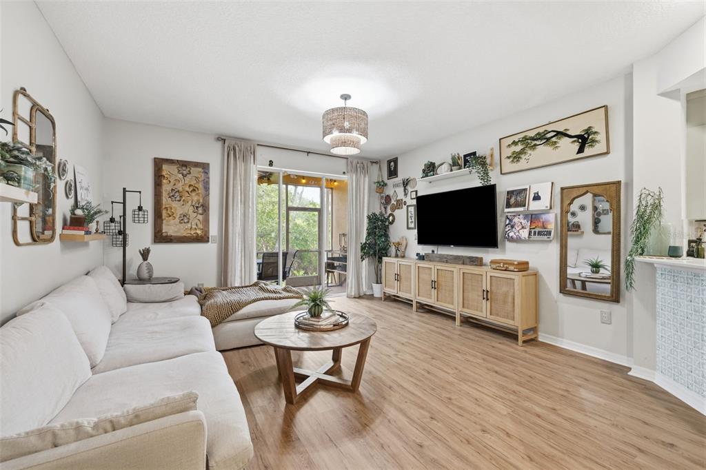A living room features a white sofa, wood coffee table, media console, and sliding glass doors — 3073 BRANCH DRIVE, CLEARWATER, FL