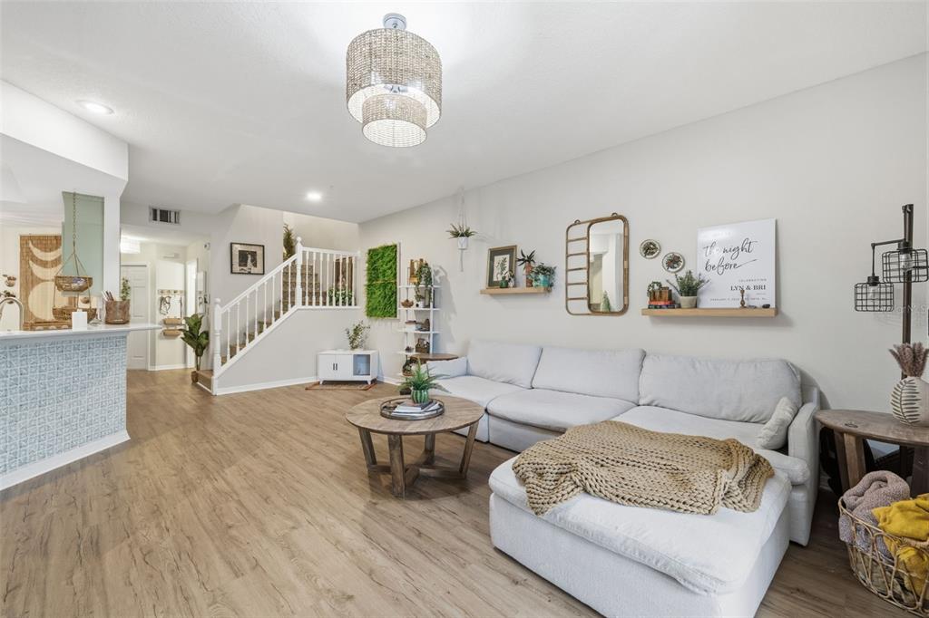 A living room features light wood flooring, a large sectional sofa, and a staircase — 3073 BRANCH DRIVE, CLEARWATER, FL