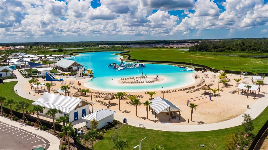 An aerial view shows a large man-made turquoise lagoon with a sandy beach and amenities — 5055 CAPTAIN DAVIS DRIVE, WIMAUMA, FL
