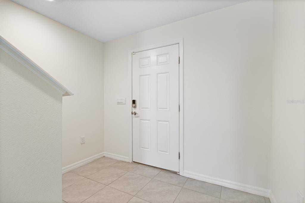 An entryway with white walls, a white door, and light-colored tile flooring — 16555 MOSAIC OAR DRIVE, WIMAUMA, FL