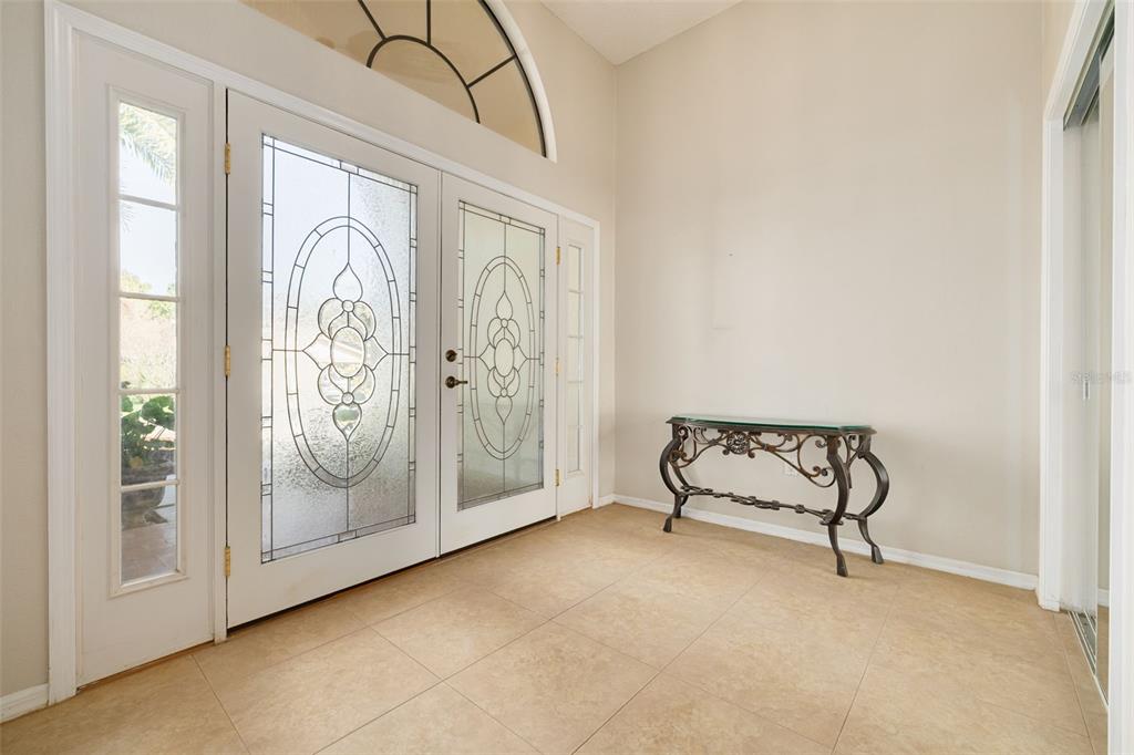 A single-story suburban house with a beige exterior, two garage doors, and a palm tree — 470 HICKORYNUT AVENUE, OLDSMAR, FL