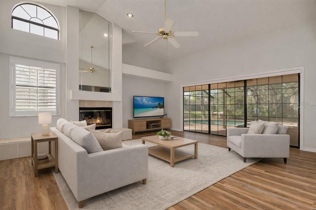 A spacious open-concept living and dining area features vaulted ceilings, wood-look flooring, and neutral decor — 470 HICKORYNUT AVENUE, OLDSMAR, FL