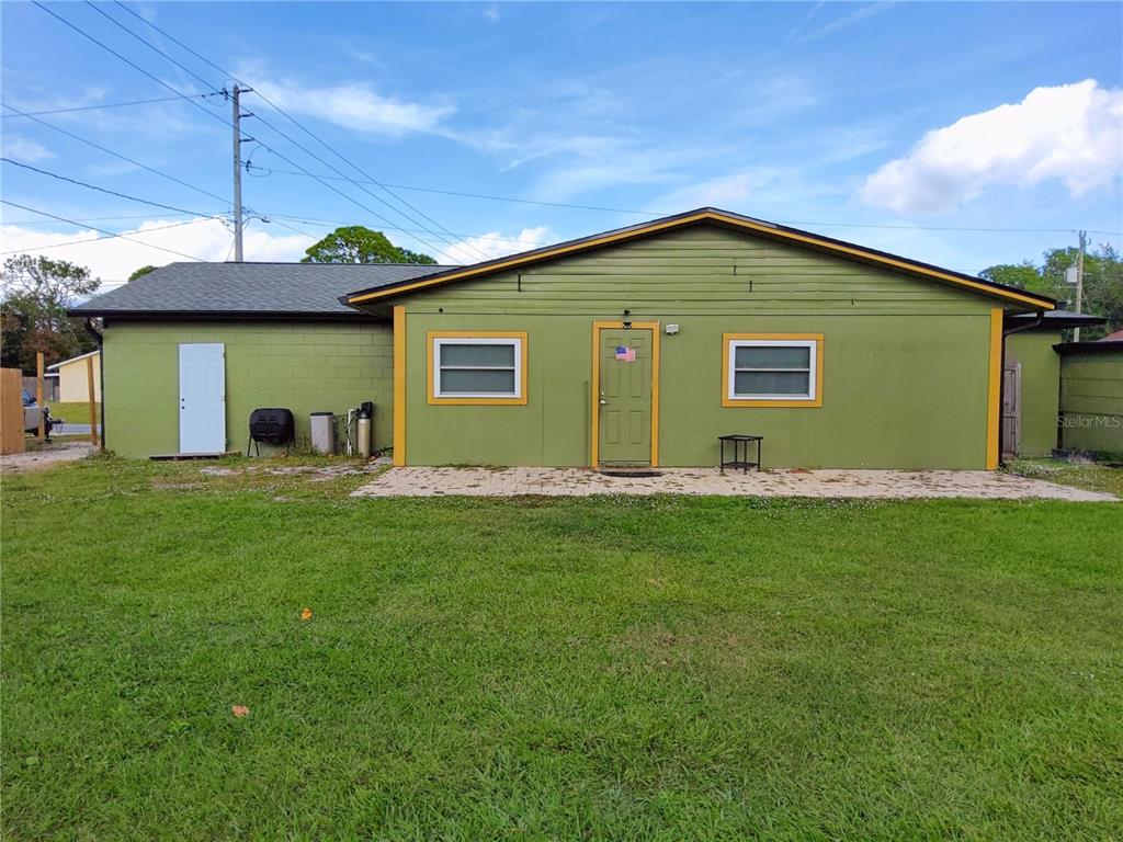 A single-story green house with a paved patio and a grassy yard — 4297 CANELA ROAD, COCOA, FL
