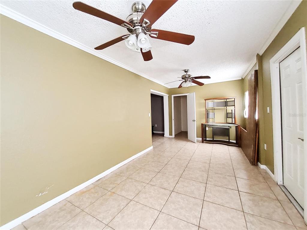 A room with tan walls, tile flooring, and two ceiling fans — 4297 CANELA ROAD, COCOA, FL