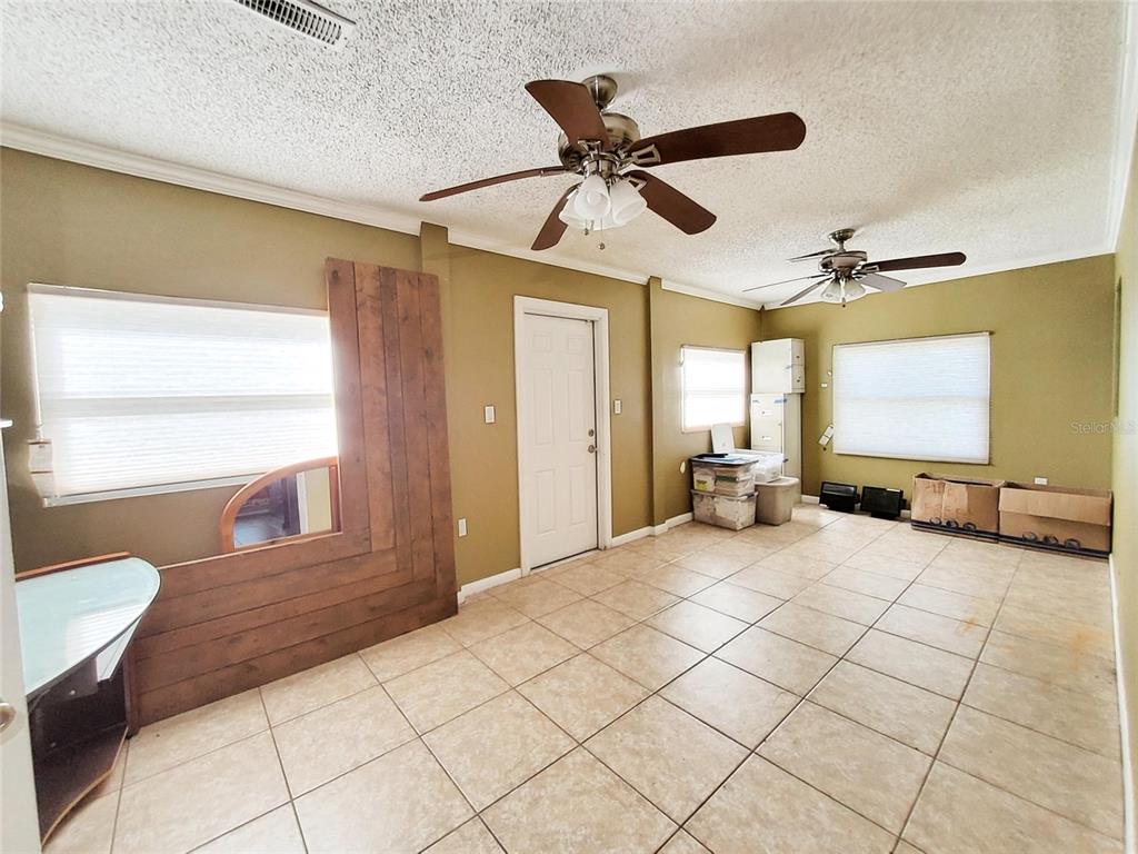A room with tan walls, tile flooring, two ceiling fans, and a wood-paneled accent wall — 4297 CANELA ROAD, COCOA, FL