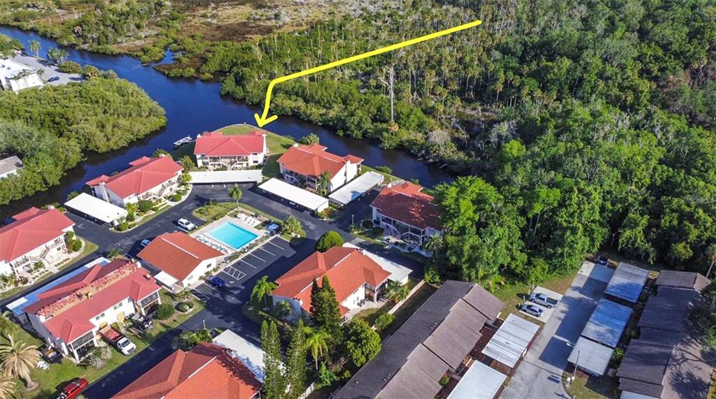 An aerial view shows a multi-building apartment complex with red roofs, a pool, and surrounding greenery — 9940 EAGLES POINT CIRCLE UNIT 4, PORT RICHEY, FL