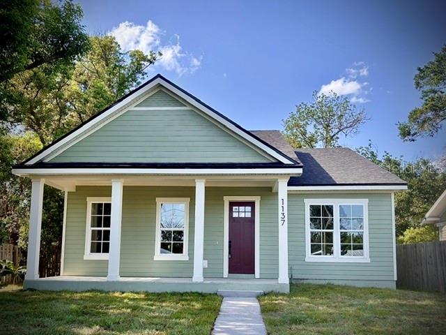 A light green house with a white garage door sits behind a chain-link fence — 1137 DOROTHY STREET, LAKELAND, FL