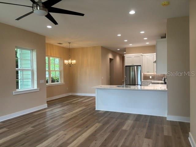 An empty room features light-colored walls, wood-look flooring, a ceiling fan, and multiple windows — 1137 DOROTHY STREET, LAKELAND, FL