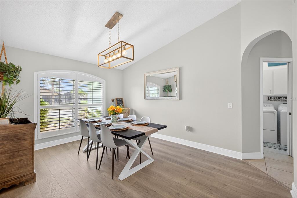 A dining room with a black table, white chairs, and a rectangular light fixture — 3907 57TH PLACE E, BRADENTON, FL