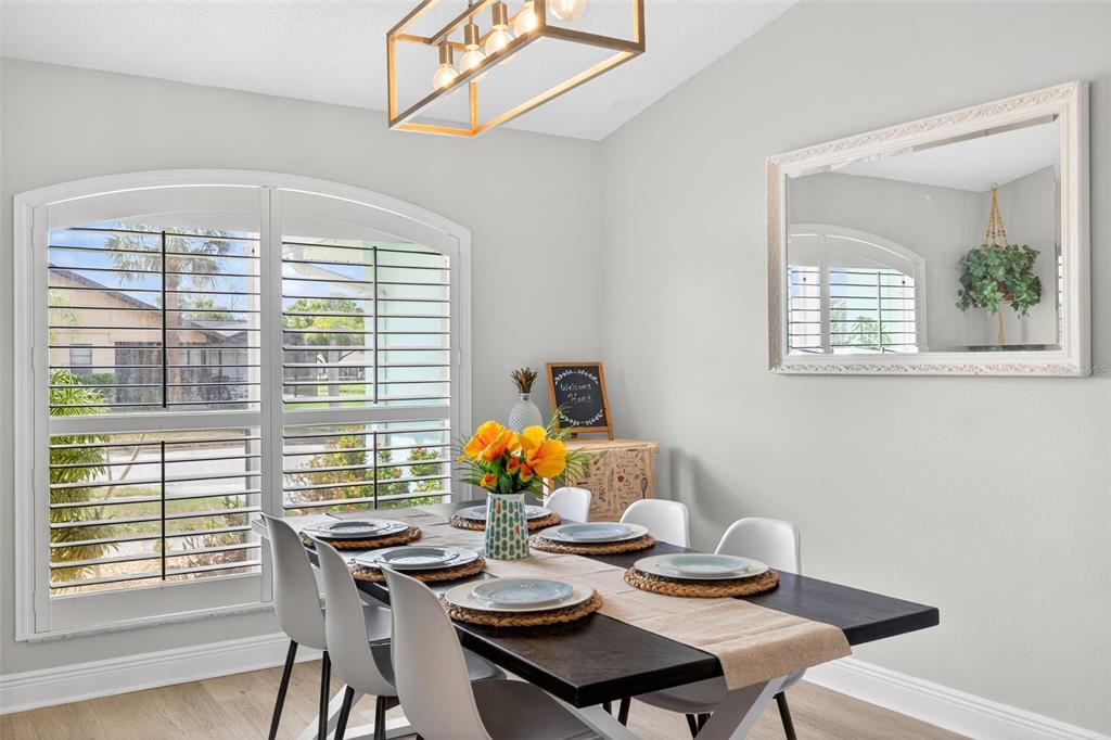 A dining room features a dark wood table, white chairs, a chandelier, and arched windows — 3907 57TH PLACE E, BRADENTON, FL