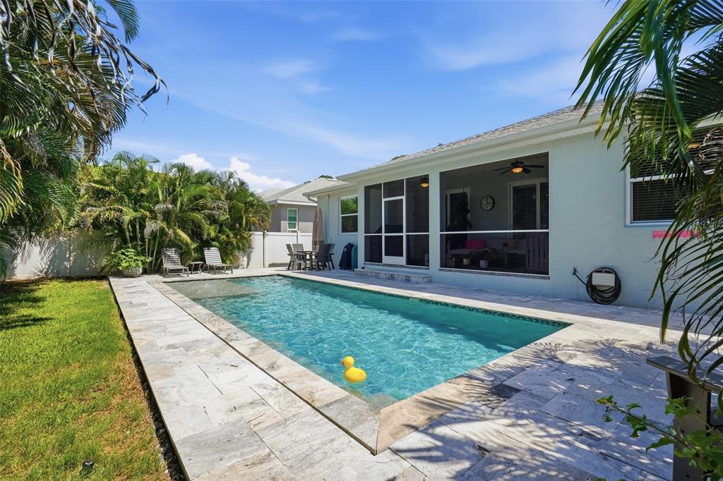 A backyard features a rectangular swimming pool with a yellow duck float and stone patio — 7859 40TH AVENUE N, ST PETERSBURG, FL