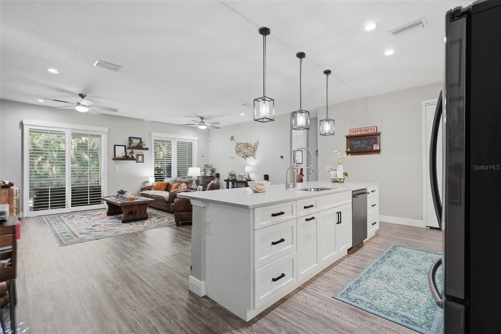 A kitchen island with white cabinets and a quartz countertop sits in an open-concept living space — 7859 40TH AVENUE N, ST PETERSBURG, FL