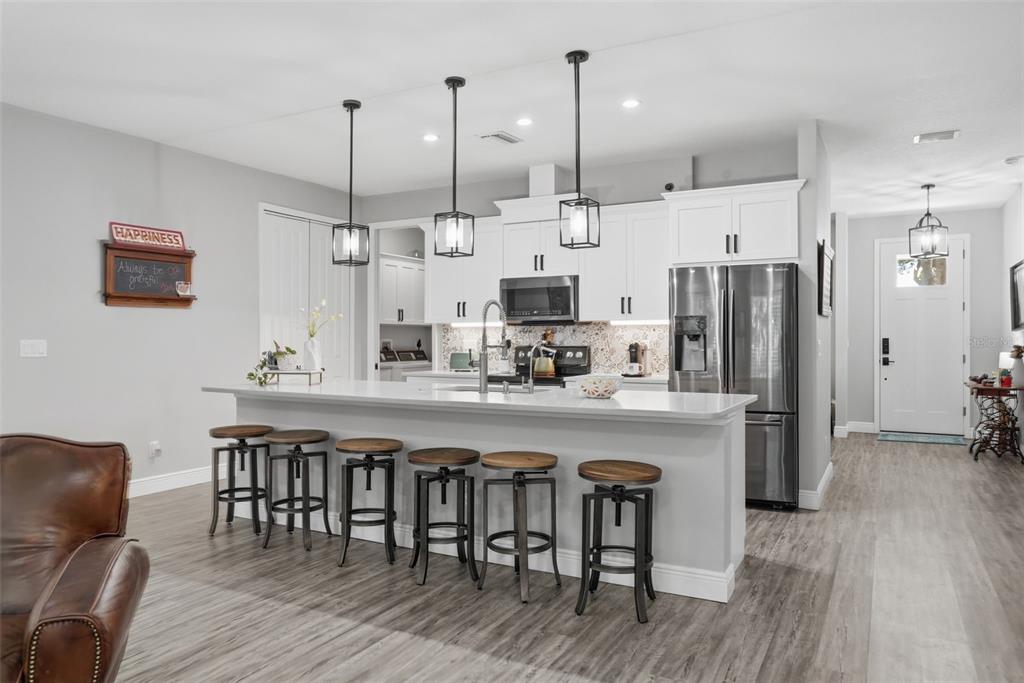 A kitchen features white cabinetry, stainless steel appliances, a quartz island, and six bar stools — 7859 40TH AVENUE N, ST PETERSBURG, FL