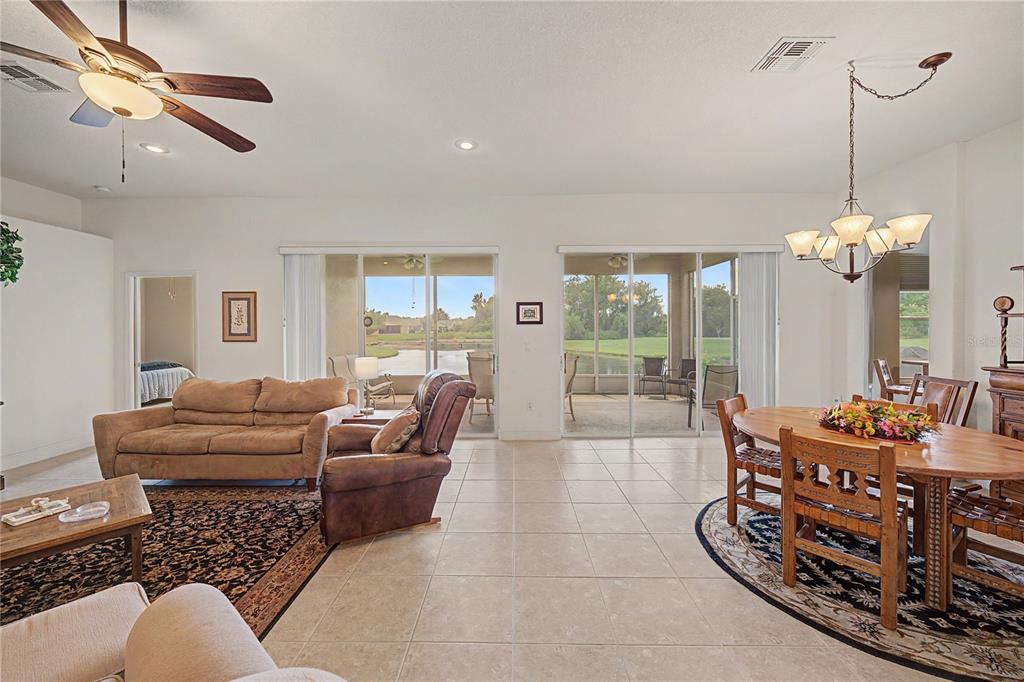 An open-concept living and dining area with tile floors, a ceiling fan, and sliding glass doors — 10231 CLEGHORN DRIVE, SAN ANTONIO, FL
