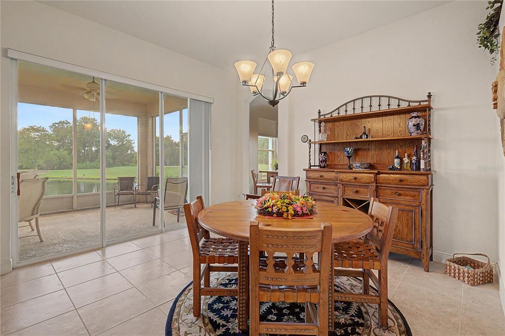 A dining room with a wooden table, chairs, hutch, and sliding doors overlooking a lake — 10231 CLEGHORN DRIVE, SAN ANTONIO, FL