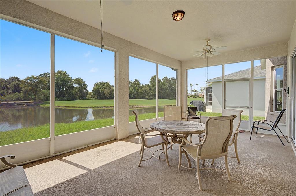 A screened-in patio with outdoor furniture overlooks a pond and a golf course — 10231 CLEGHORN DRIVE, SAN ANTONIO, FL
