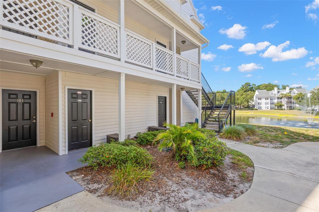 A multi-story apartment building with a parking lot and several parked cars in front — 3310 HAVILAND COURT UNIT 104, PALM HARBOR, FL