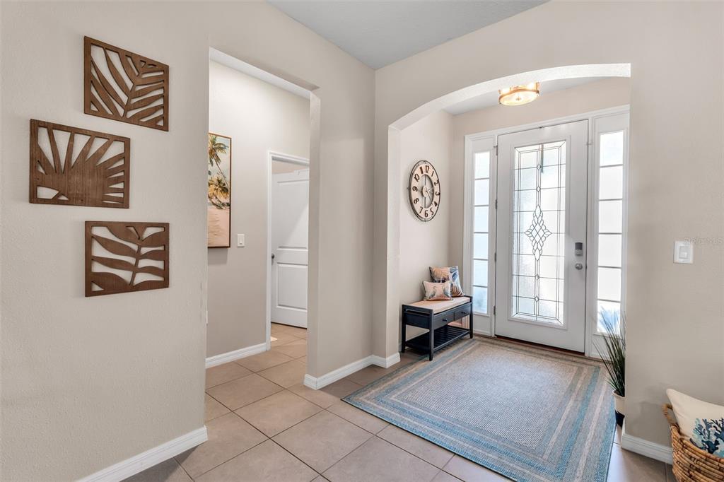 A tiled entryway features a front door with glass panels, a wall clock, and bench seating — 13225 WATERLEAF GARDEN CIRCLE, RIVERVIEW, FL