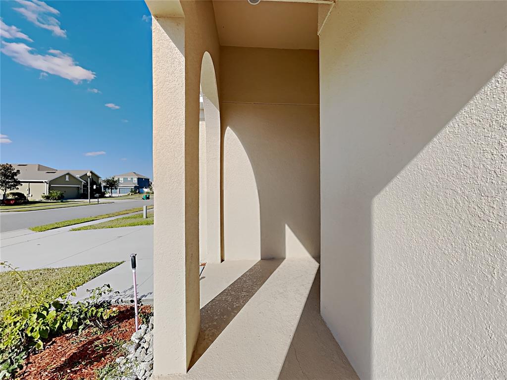 A view from a covered entryway looking out toward a suburban street and houses — 1328 ARONIMINIK DRIVE, MOUNT DORA, FL