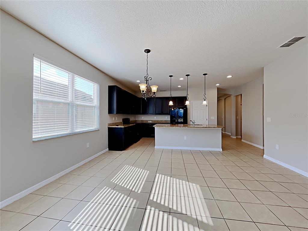 A kitchen with dark cabinets, a granite island, and tile flooring in an open space — 1328 ARONIMINIK DRIVE, MOUNT DORA, FL