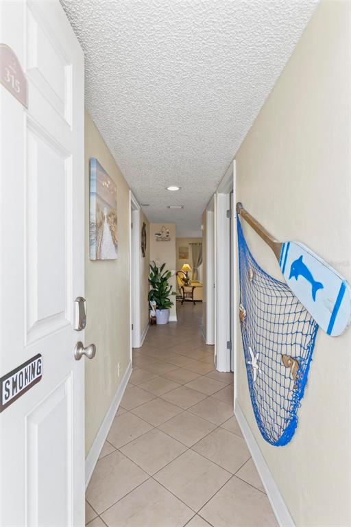 A hallway with tile floors features a decorative fishing net and paddle on the wall — 2700 OCEAN SHORE BOULEVARD UNIT 315, ORMOND BEACH, FL
