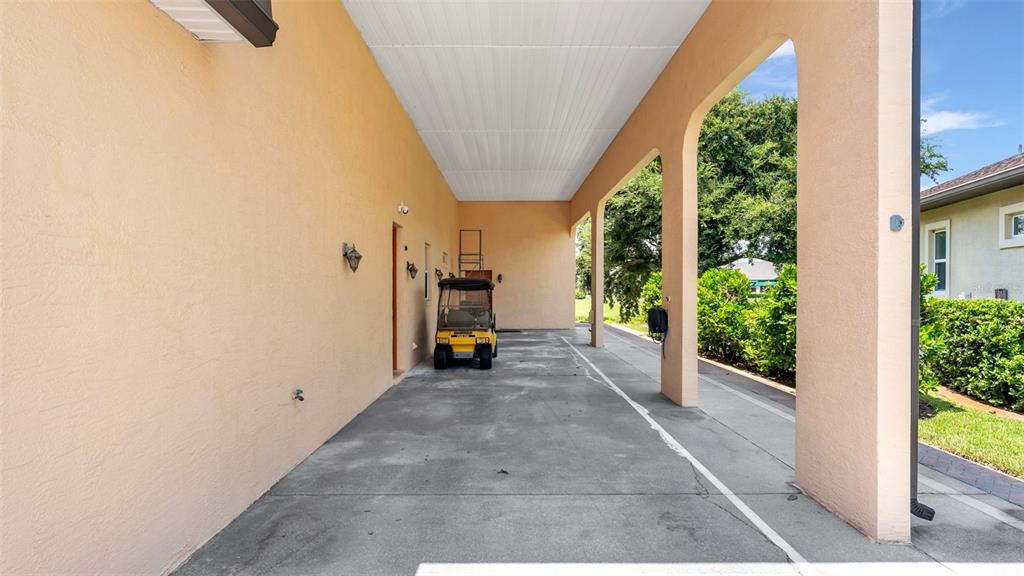 A covered outdoor carport with a concrete floor, arched pillars, and a golf cart — 1230 MOTORCOACH DRIVE, POLK CITY, FL