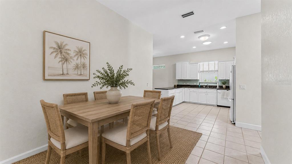 A dining area with a wooden table and chairs sits adjacent to a white kitchen — 1230 MOTORCOACH DRIVE, POLK CITY, FL