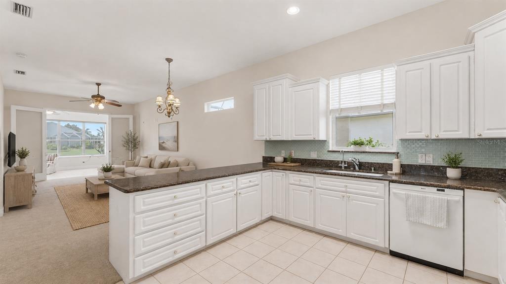 A white kitchen with dark countertops overlooks a living room with a ceiling fan — 1230 MOTORCOACH DRIVE, POLK CITY, FL