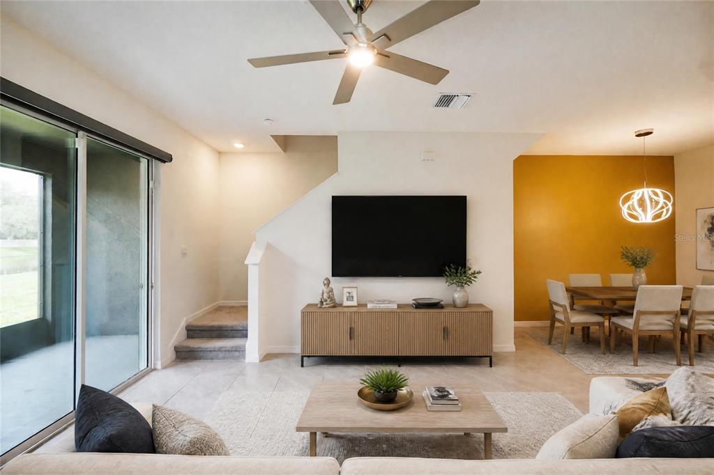 A living room features a wall-mounted television, a wooden media console, and an adjacent dining area — 34347 SORREL MINT DRIVE, WESLEY CHAPEL, FL