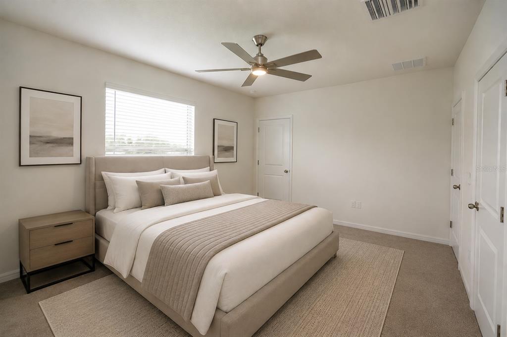 A bedroom features a neutral color palette, a platform bed, a ceiling fan, and carpet — 34347 SORREL MINT DRIVE, WESLEY CHAPEL, FL