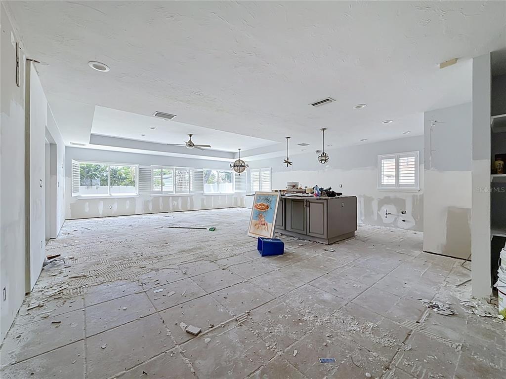 An unfinished open-concept kitchen and living area with exposed tile flooring and drywall patches — 2010 BAYOU GRANDE BOULEVARD NE, ST PETERSBURG, FL