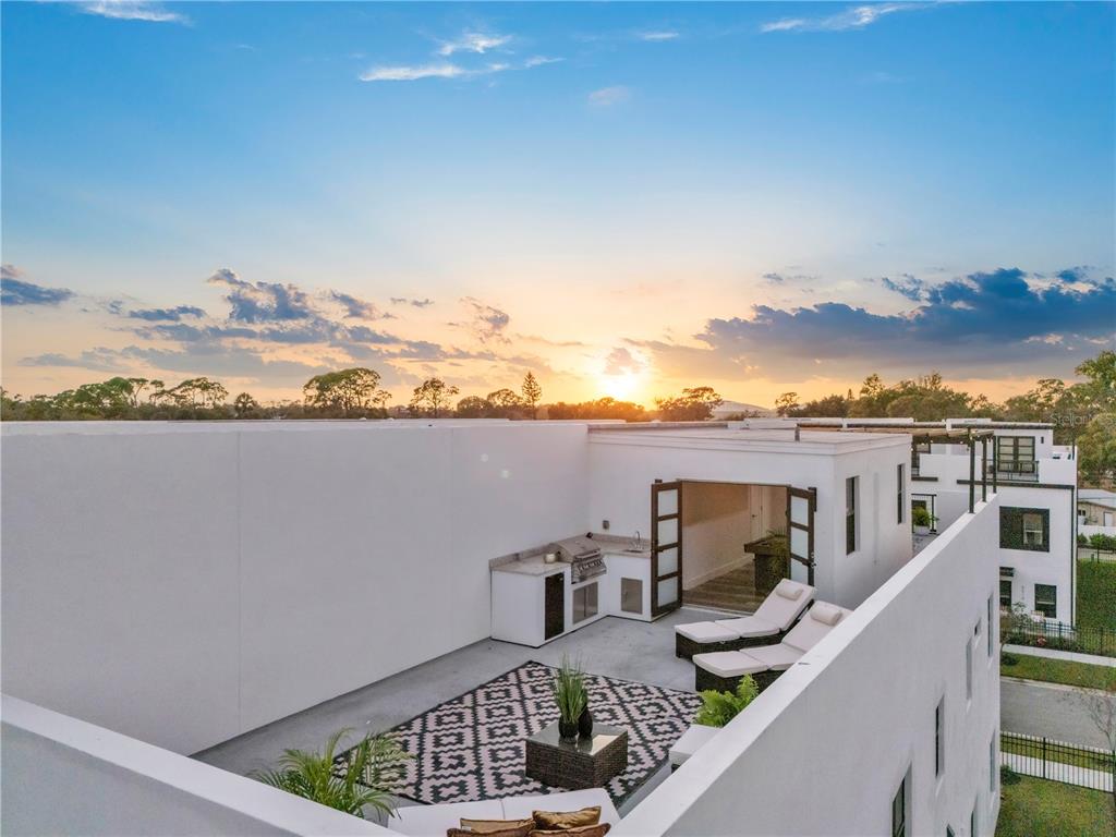 A rooftop terrace features a built-in outdoor kitchen, lounge chairs, and a patterned area rug — 6207 64TH WAY N, PINELLAS PARK, FL