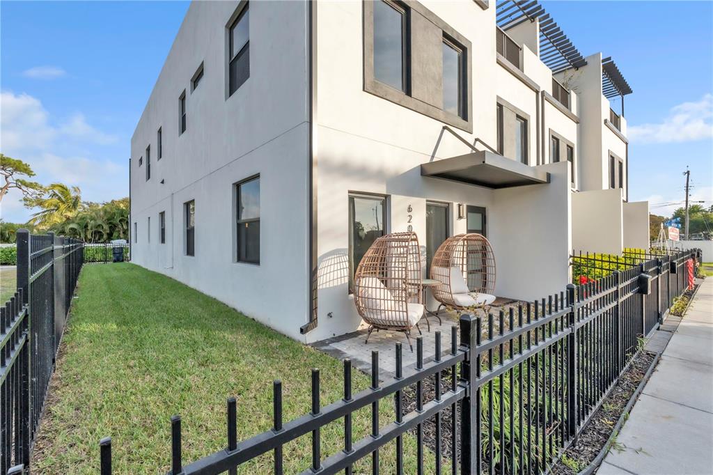 A modern white townhouse exterior features a small patio with two wicker egg chairs — 6207 64TH WAY N, PINELLAS PARK, FL
