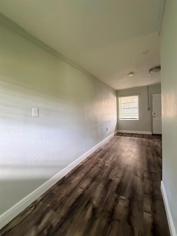 An empty room with light green walls, wood-look flooring, a window, and a white door — 16710 WALLACE, UMATILLA, FL