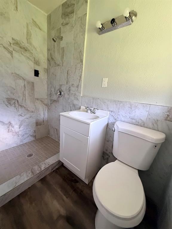 A bathroom featuring a walk-in tiled shower, a white vanity, and a toilet — 16710 WALLACE, UMATILLA, FL