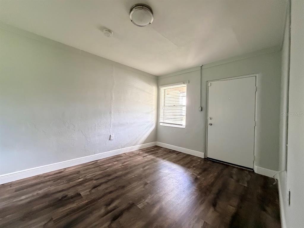A room with light gray walls, wood-look flooring, a single window, and a white door — 16710 WALLACE, UMATILLA, FL