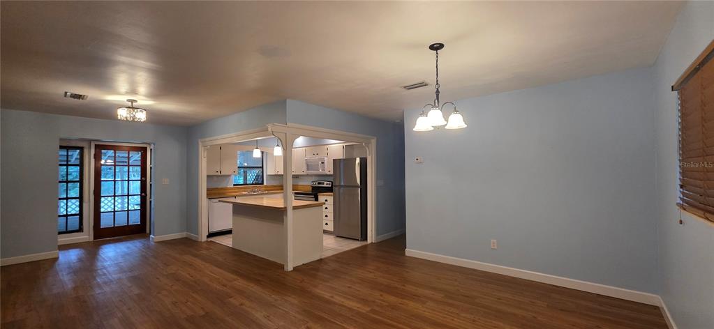 An open-concept kitchen with white cabinets and a breakfast bar overlooks a dining area — 17451 SOUTHSIDE COURT, HIGH SPRINGS, FL