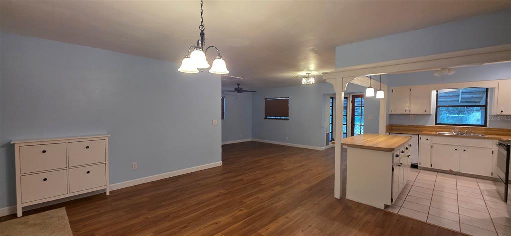 An open-concept kitchen and dining area features light blue walls, wood flooring, and white cabinetry — 17451 SOUTHSIDE COURT, HIGH SPRINGS, FL