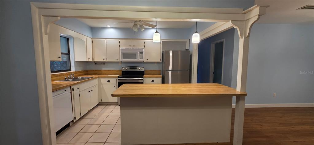 A kitchen features white cabinets, a wooden countertop island, and stainless steel appliances — 17451 SOUTHSIDE COURT, HIGH SPRINGS, FL