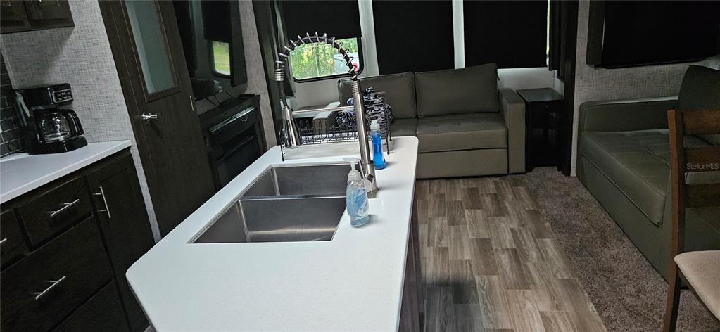 A kitchen island with a double sink and faucet sits before a living area — 3000 CLARCONA ROAD UNIT 2710, APOPKA, FL