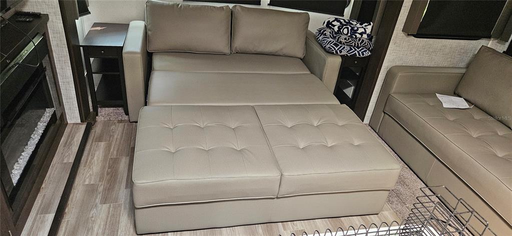 A living area features a light-colored convertible sofa bed, a fireplace, and wood-look flooring — 3000 CLARCONA ROAD UNIT 2710, APOPKA, FL