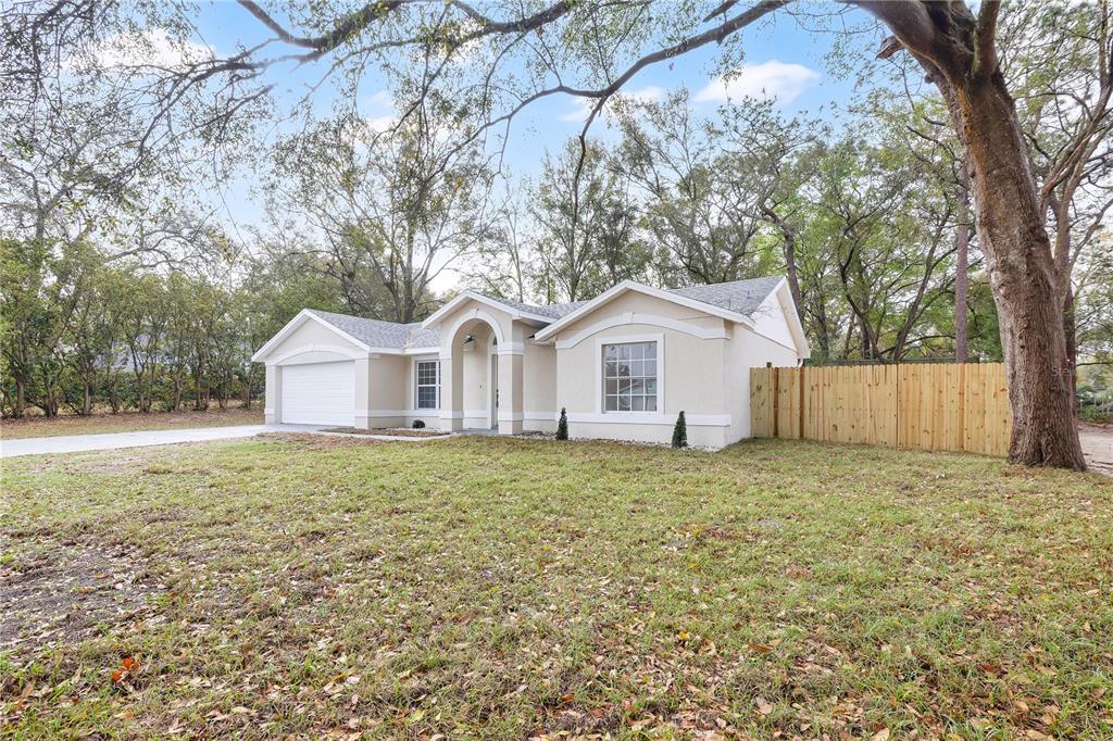 A single-story house with a beige stucco exterior, a two-car garage, and a wooden fence — 1120 DUNBRIDGE STREET, APOPKA, FL
