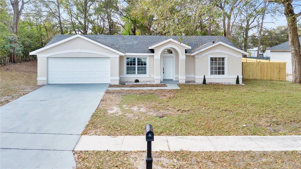A single-story house with a beige exterior, a white garage door, and a front lawn — 1120 DUNBRIDGE STREET, APOPKA, FL