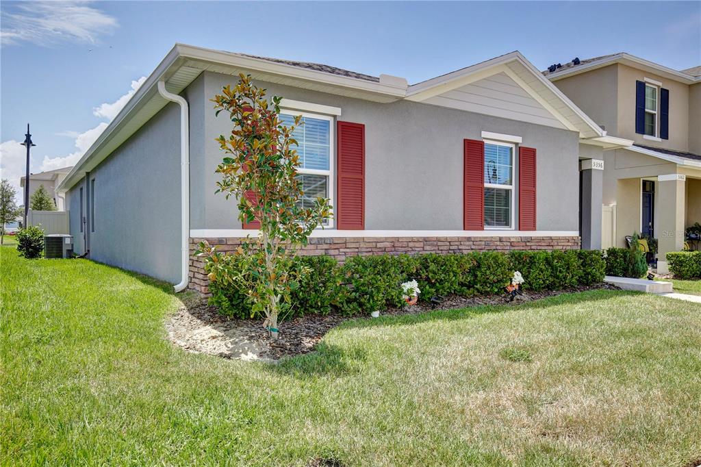 A single-story house with gray stucco, red shutters, and a stone veneer base — 5356 HAYLOFT DRIVE, APOPKA, FL