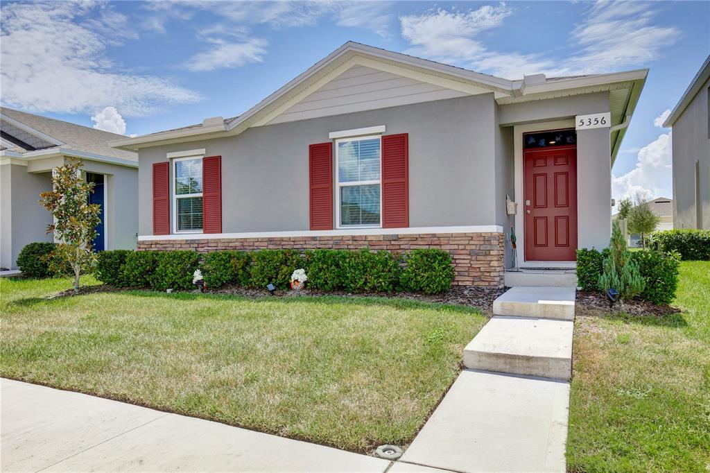 A single-story house with gray stucco walls, red shutters, and a stone veneer base — 5356 HAYLOFT DRIVE, APOPKA, FL