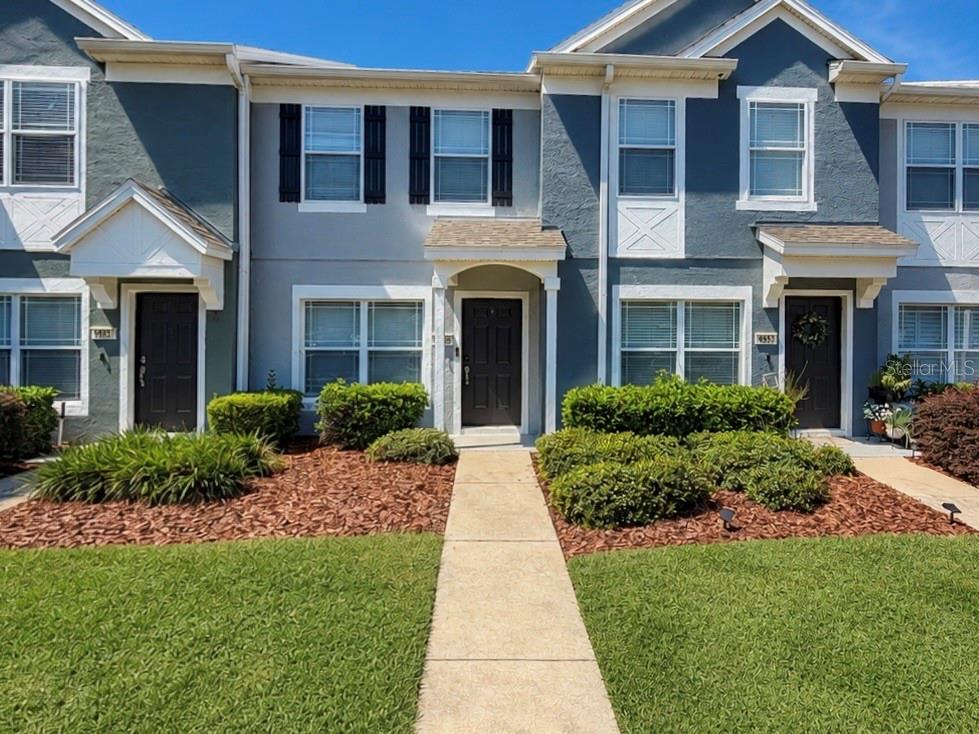 A row of three two-story townhomes with dark doors, gray siding, and small front porches — 4452 SW 49TH AVENUE, OCALA, FL