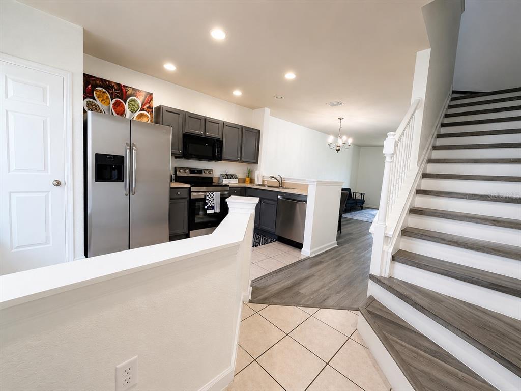 A kitchen with dark cabinets and stainless steel appliances sits beside a staircase with wood treads — 4452 SW 49TH AVENUE, OCALA, FL