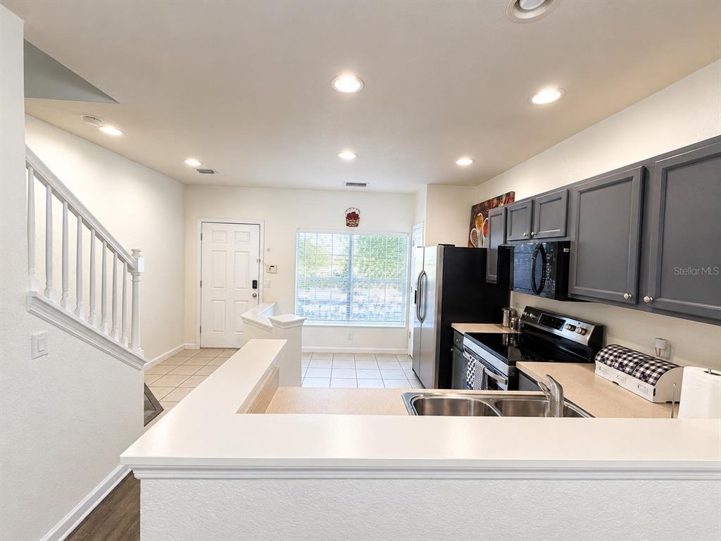 A kitchen with gray cabinets and a breakfast bar overlooks a dining area and stairs — 4452 SW 49TH AVENUE, OCALA, FL